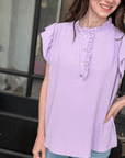 Woman wearing lavender ruffle trim sleeveless boutique top