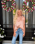 Woman wearing blush leopard jacquard tie neck blouse with denim jeans