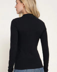 A woman shown from the back wearing a fitted black long-sleeve mock neck top and blue jeans against a plain light background.