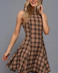 Woman wearing a brown plaid dress against a gray background