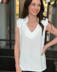 Woman wearing off white ruffle sleeve v-neck blouse from Halemi & Co.