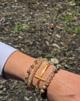 White Christian bracelet stack featuring a horizontal gold cross with crystal and wood bead stretch bracelets.