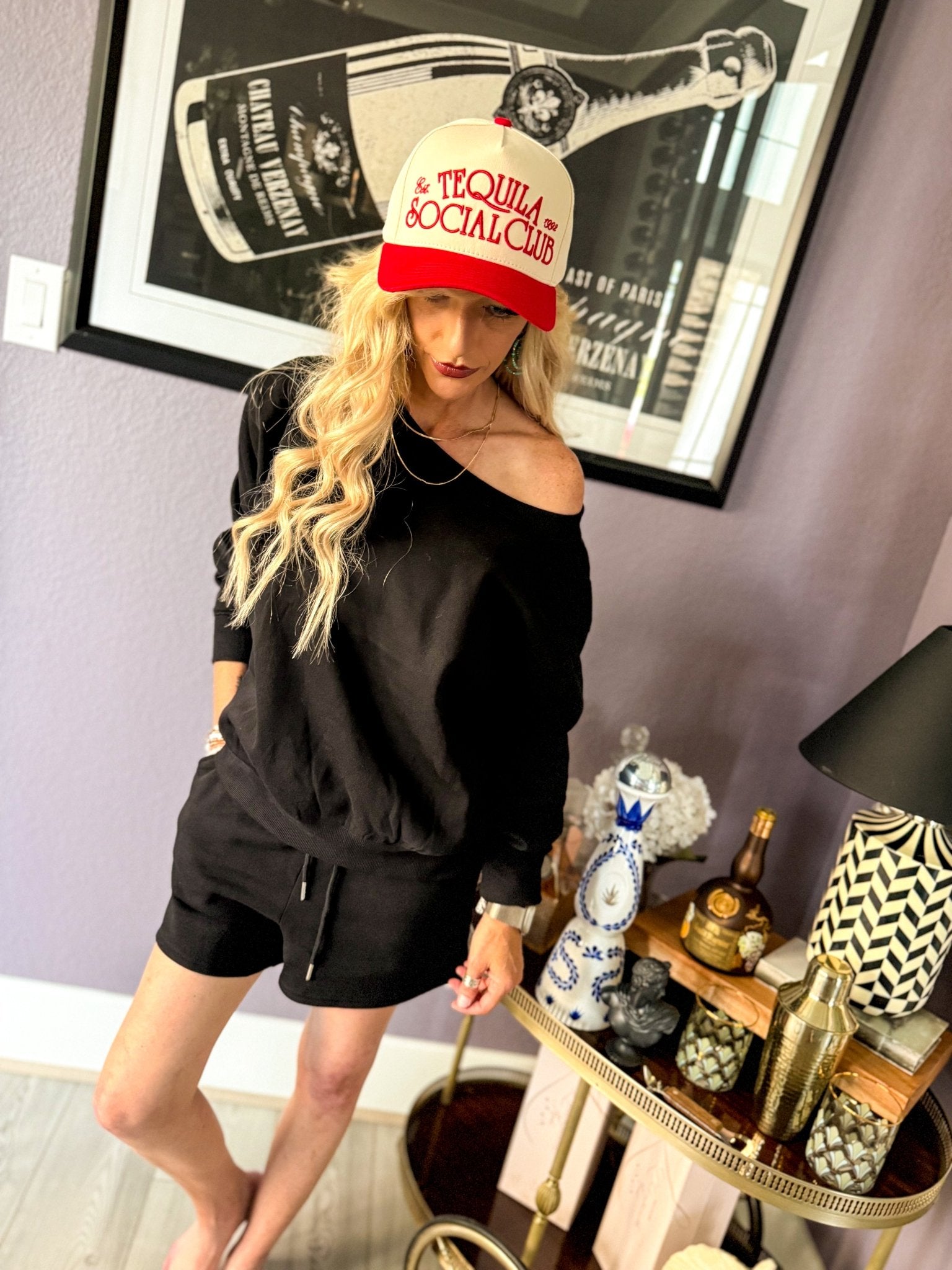 Woman wearing the Black French Terry Lounge Short Set featuring a relaxed boat neck sweatshirt, matching shorts with pockets, and soft French terry fabric.
