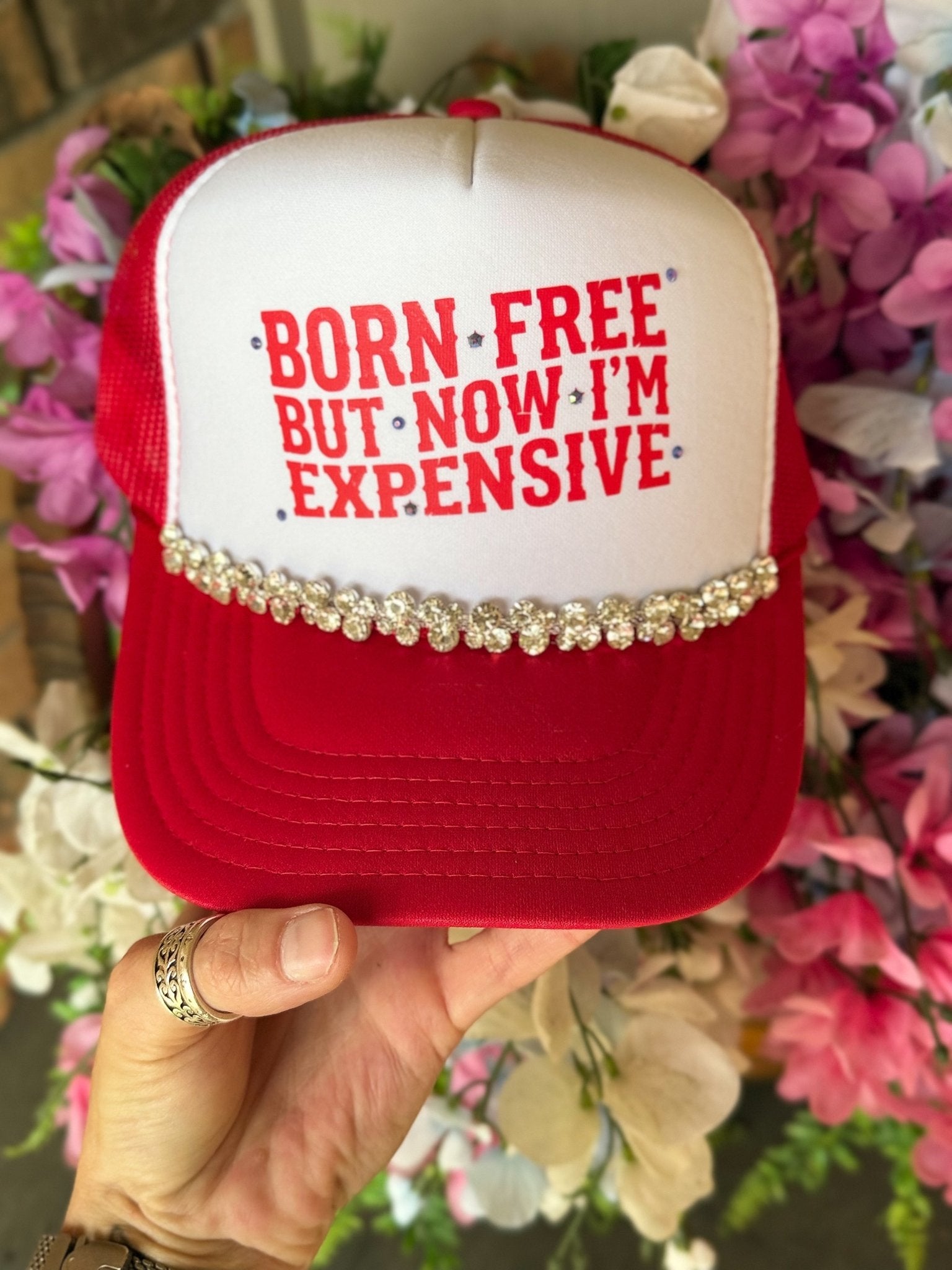Woman wearing the Born Free But Now I'm Expensive trucker hat with  front design and adjustable snapback closure.