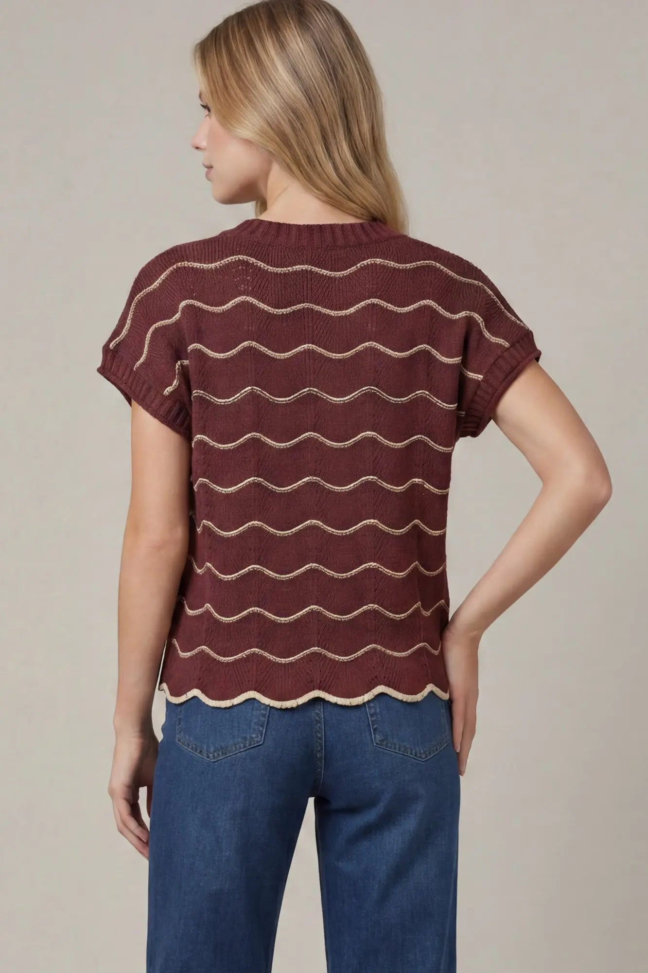 Back view of a burgundy striped knit sweater top with scalloped hem and short sleeves.