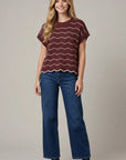 Front view of a burgundy scalloped knit sweater top featuring cream wave stripes, drop shoulders, and a relaxed fit.