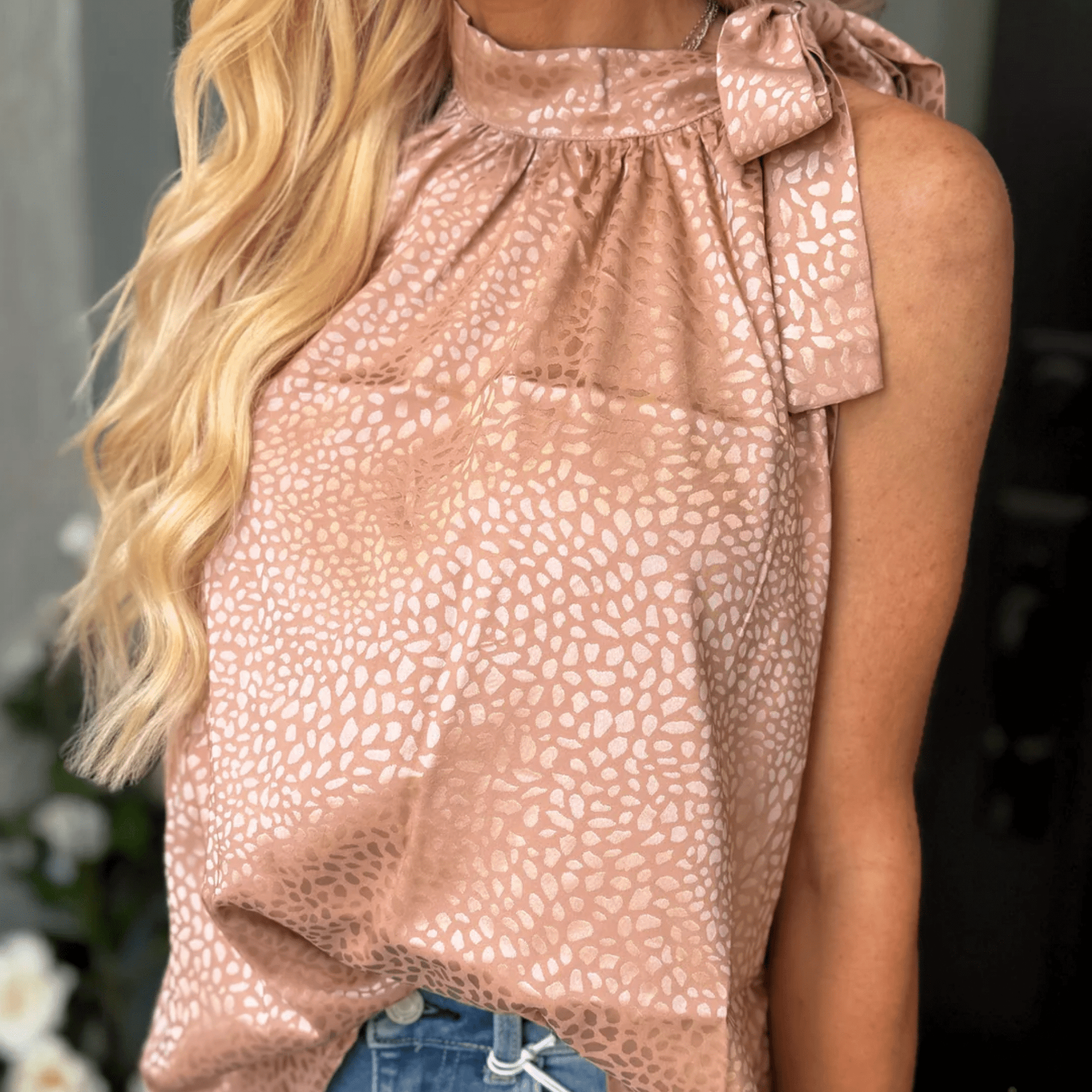 Close-up of blush leopard jacquard blouse with feminine tie neck detail