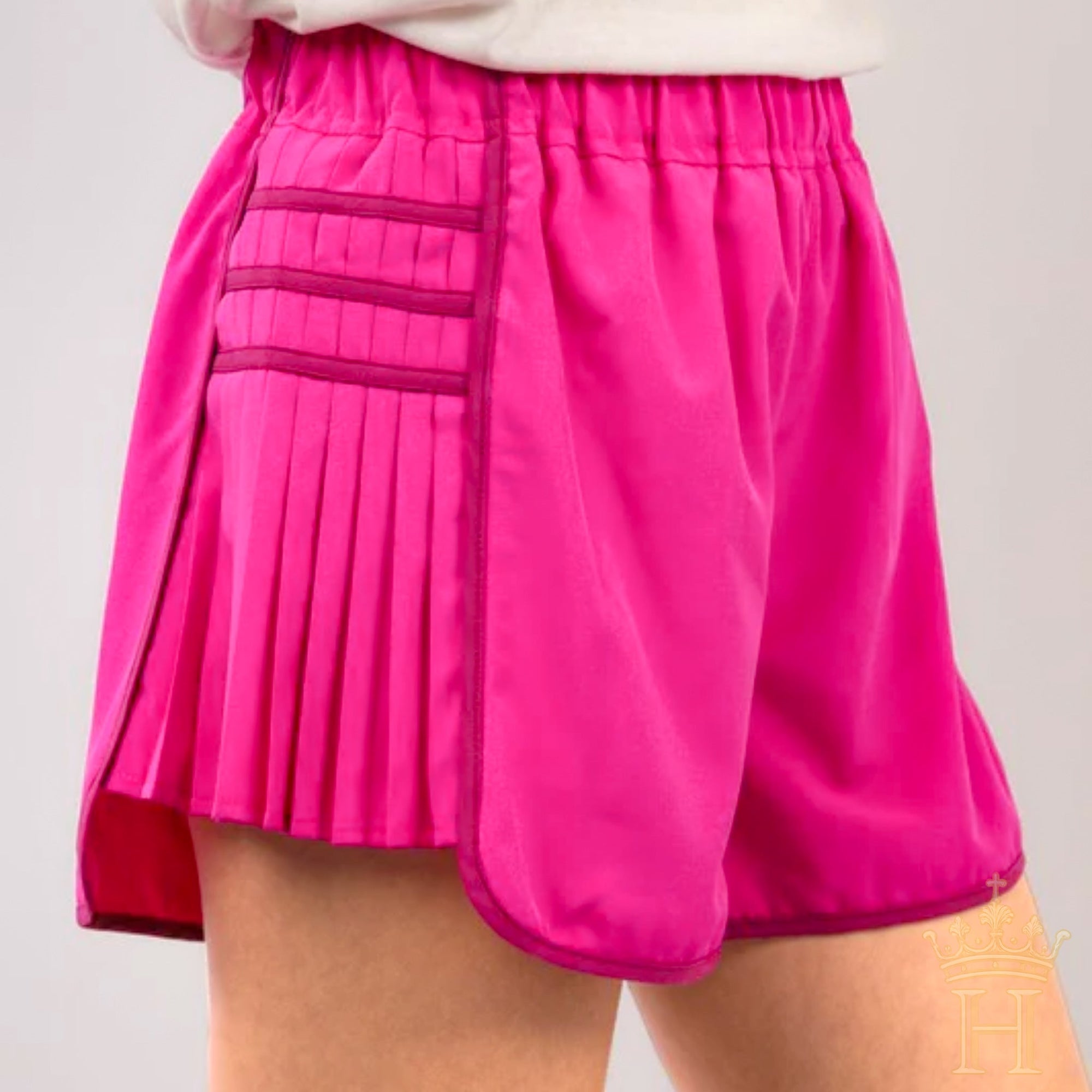 Women wearing hot pink pleated athletic shorts styled for athleisure fashion