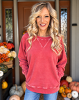 Woman wearing a washed dark red French terry pullover with ribbed V-inset neckline and side pockets, styled with blue jeans.