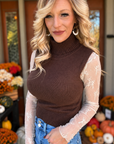 Light mocha sheer floral lace top styled underneath a brown sleeveless turtleneck sweater with blue jeans, showing floral lace sleeves.
