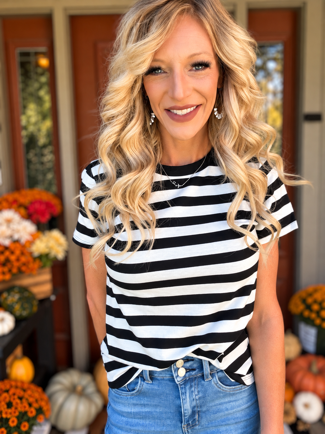 Model wearing the Stripe Soft Knit Tee featuring bold black and white horizontal stripes, short sleeves, and a relaxed fit, styled with light-wash blue jeans for a chic, casual everyday outfit.