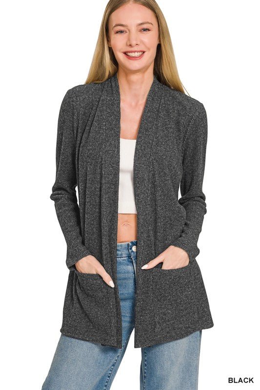 Woman modeling a heathered black ribbed open front cardigan with long sleeves and two front pockets, styled with jeans.