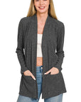 Woman modeling a heathered black ribbed open front cardigan with long sleeves and two front pockets, styled with jeans.