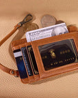 Brown leather wallet with cards, money, and coins on a beige surface