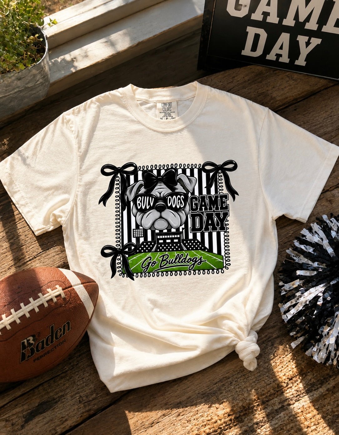 Cream women’s Bulldogs game day graphic tee with football field, bows and bulldog design