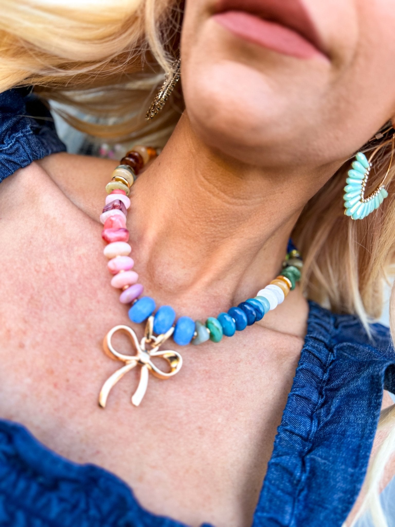 Rainbow gemstone-style beaded necklace with multicolor beads and a polished gold bow charm.