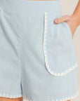 Close-up of scallop trim detailing on sky blue boutique shorts