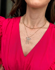 Layered gold-tone necklace with sparkling crystal bow pendant and coordinating crystal stud earrings.