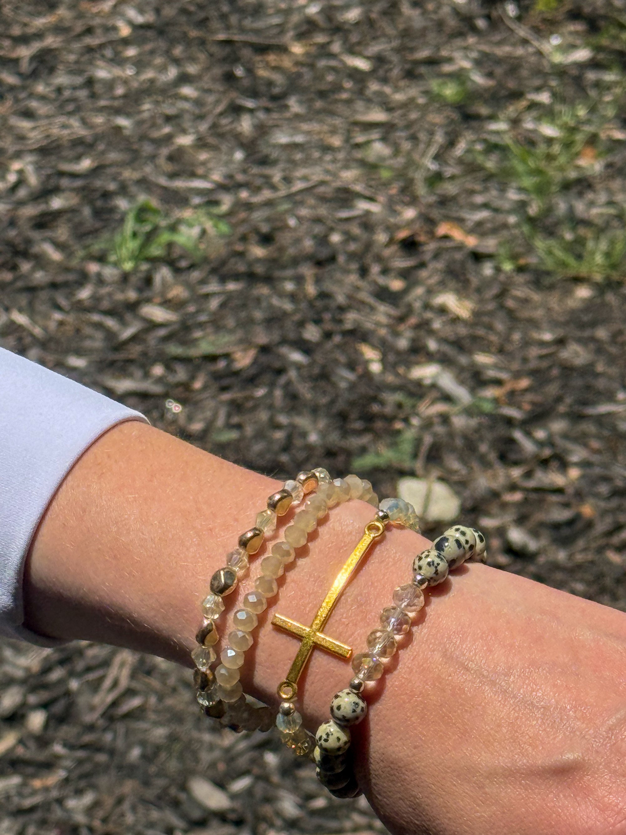 White Christian bracelet stack featuring a horizontal gold cross with crystal and wood bead stretch bracelets.